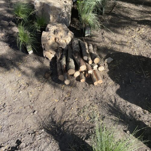 Two limestone boulders, a pile of cut logs and a collection of native grasses are grouped together in the pollinator garden creating a complex "island" of urban habitat.