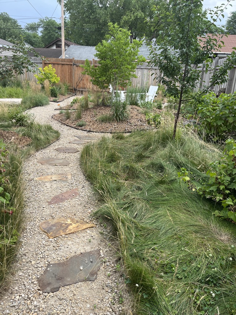 meandering paver path set in gravel amongst now low lawn, mini orchard, and native garden beds