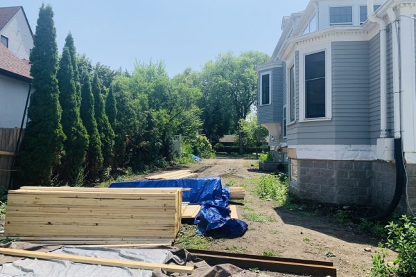 The narrow side yard of a stately Neo-Georgian home in the Kenwood neighborhood of Minneapolis, has been stripped of turf and shows signs of continued construction.